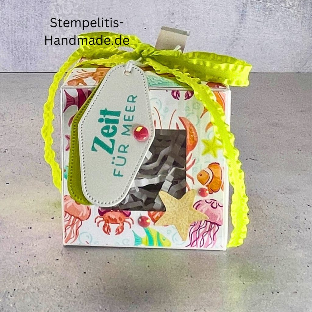 Handdekorierte Fensterschachtel 7 cm mit maritimen Motiven, Geschenkbox mit Fenster und Schleife in Grün, Detailansicht Geschenkschachtel Etikett „Zeit für Meer“, Offene Sichtfensterbox von oben, Fensterschachtel mit bunter Meeresdekoration, Geschenkverpackung mit transparentem Fenster, Handgemachte maritime Fensterschachtel mit Schleife